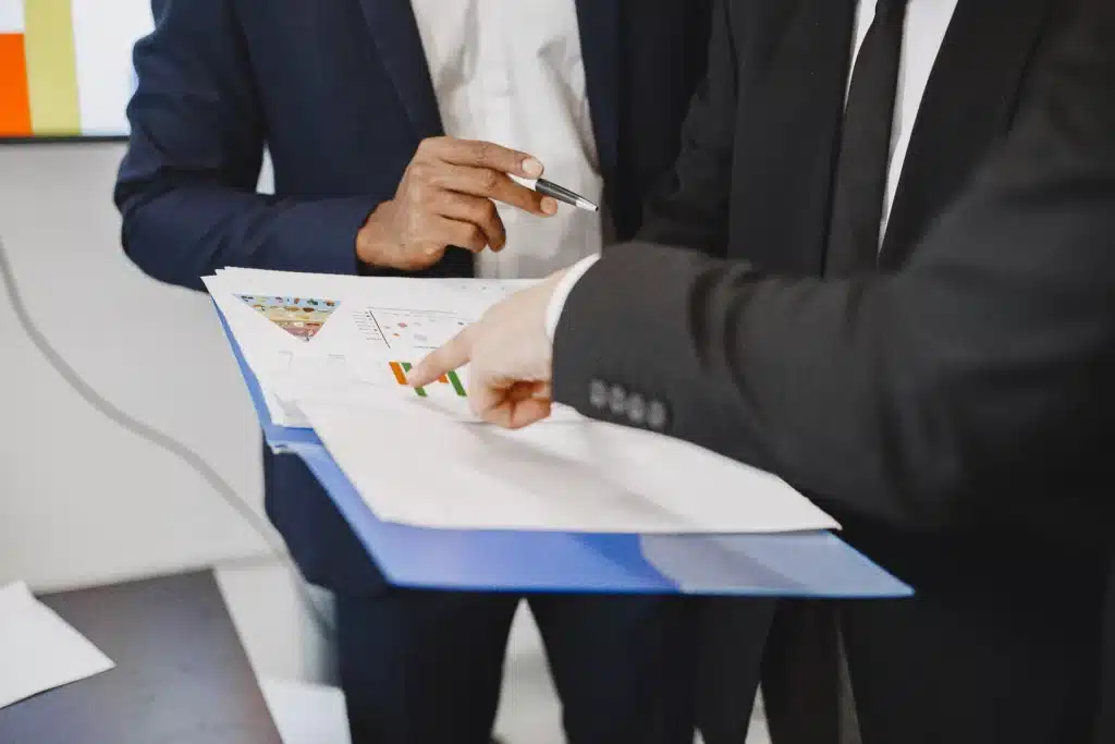 Two professionals reviewing progress charts and compliance reports in a business setting.