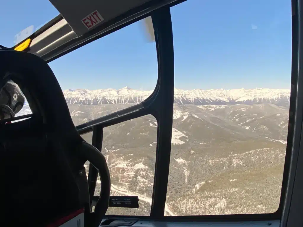Passenger cabin window view of Elbow Lake and the Opal Range in winter on an L R Helicopters helicopter tour from Calgary, Alberta