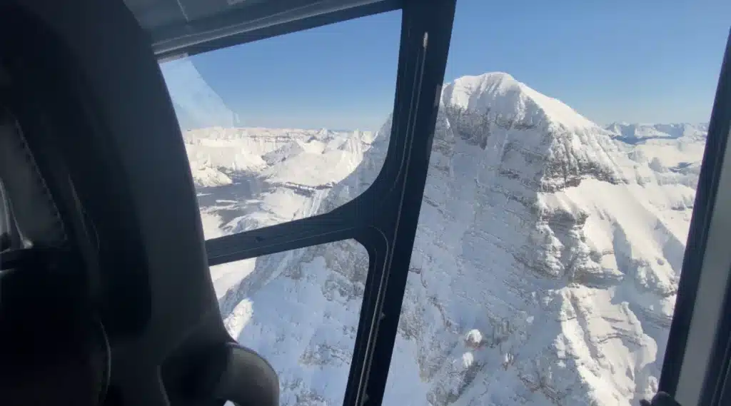 Passenger window view of snow-covered Mount Assiniboine and glaciated valleys on an L R Helicopters tour from Calgary, Alberta