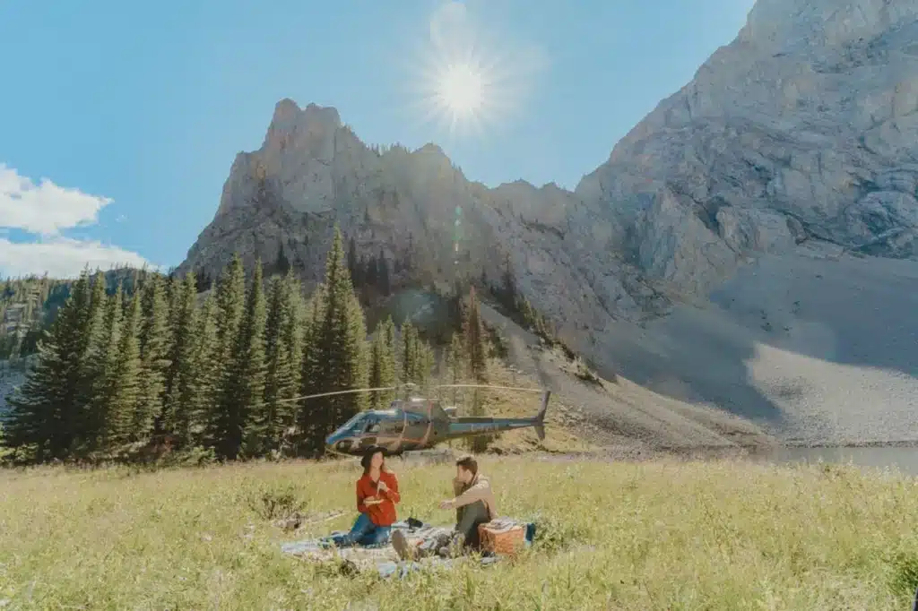 Couple enjoying a helicopter picnic in an alpine meadow at Weary Lake in the Alberta Rockies with L R Helicopters near Calgary